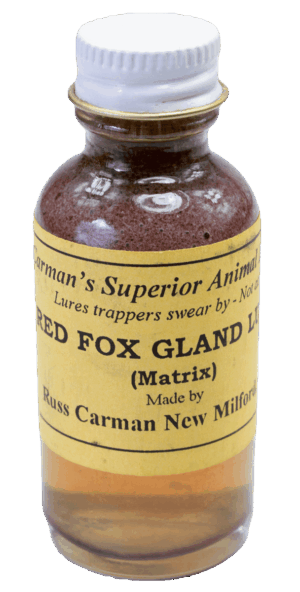 A small glass bottle labeled "Carman's Red Fox Gland Lure," containing reddish liquid, made by Carman's Superior Trapping Lures.