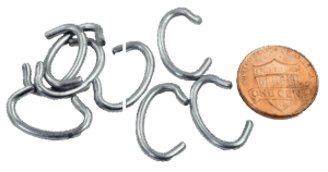 A set of small open metal Trap Tag Fasteners, similar to a copper coin for size comparison, lies scattered.